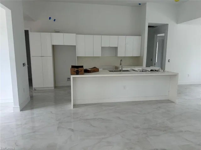 Kitchen with sink, white cabinetry, a kitchen island with sink, and light tile patterned floors