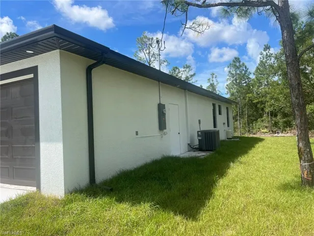 View of side of property with a lawn and central AC unit