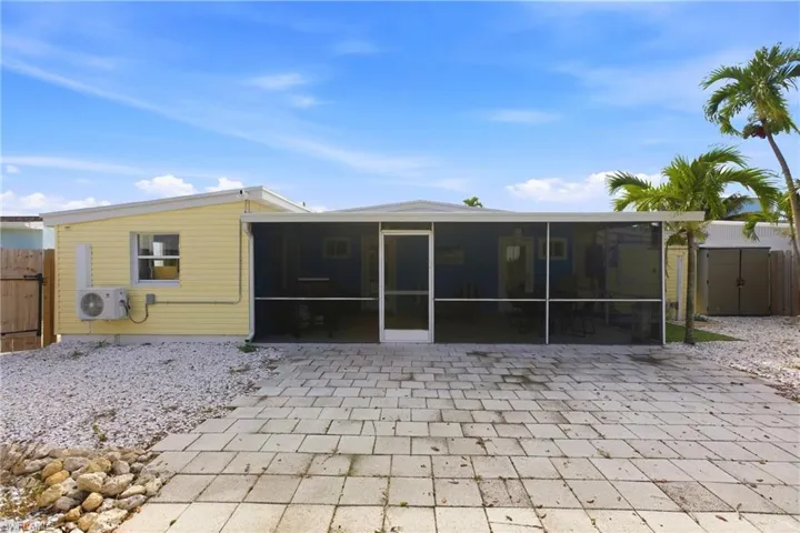 Rear view of property with a sunroom, a shed, a patio, and a gate