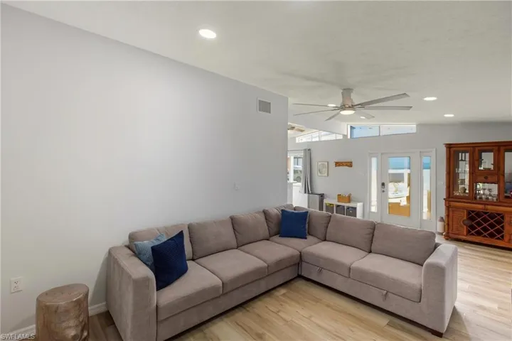 Living room with lofted ceiling, recessed lighting, light wood-style floors, and a ceiling fan