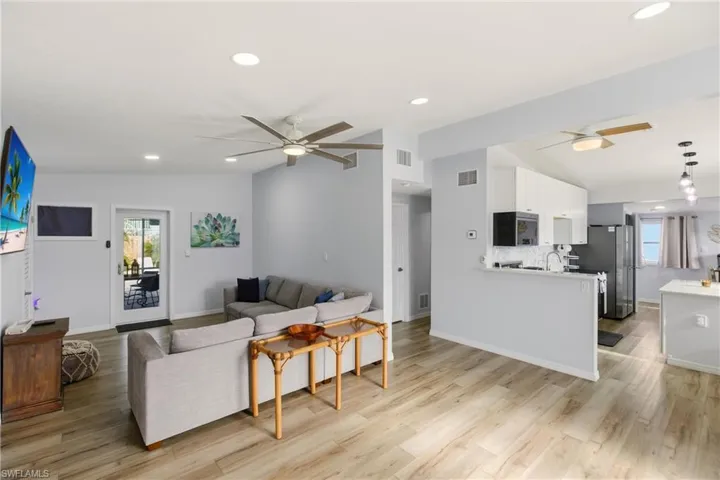 Living area with a ceiling fan, plenty of natural light, vaulted ceiling, recessed lighting, and light wood finished floors