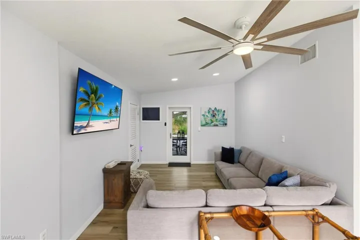 Living area featuring lofted ceiling, wood finished floors, recessed lighting, and a ceiling fan
