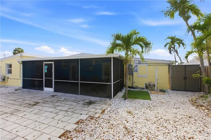 Back of property with a sunroom and a storage unit