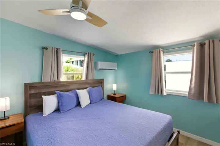 Bedroom with a ceiling fan, lofted ceiling, an AC wall unit, and wood finished floors