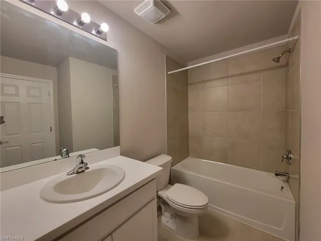 Full bathroom featuring vanity, toilet, tiled shower / bath, and tile patterned flooring