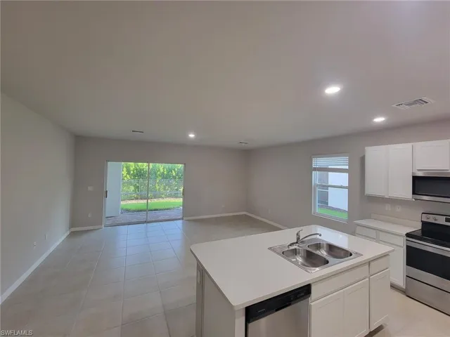 Kitchen with sink, light tile patterned floors, an island with sink, and stainless steel appliances
