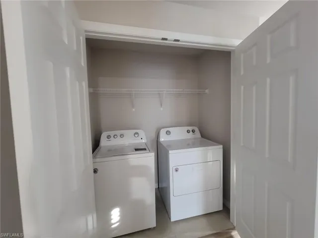 Clothes washing area with washing machine and dryer and light tile patterned floors