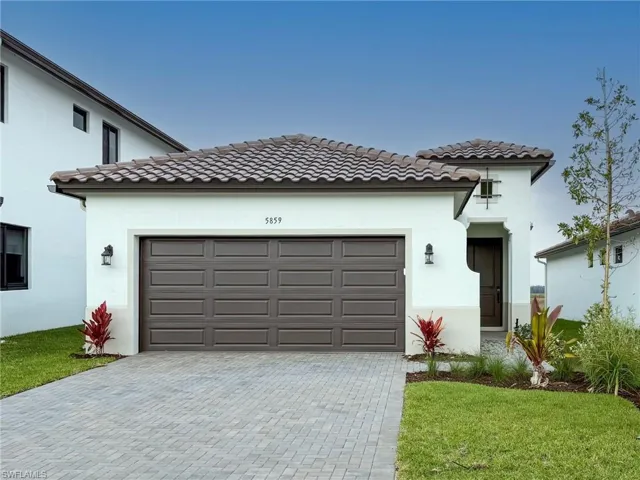 Mediterranean / spanish-style house featuring an attached garage, decorative driveway, stucco siding, a tiled roof, and a front lawn