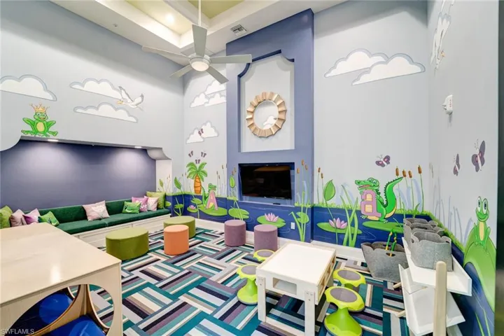 Rec room featuring a high ceiling, a fireplace, and ceiling fan