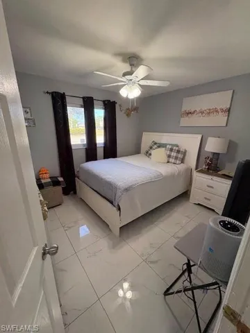 Bedroom featuring light marble finish flooring and a ceiling fan