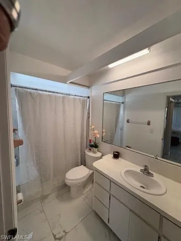 Bathroom with vanity, a shower with curtain, and light marble finish floors