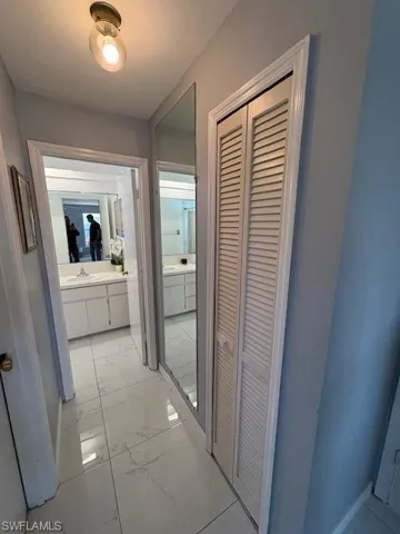 Hall with light marble finish flooring and a sink