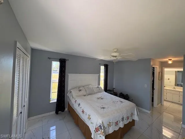 Bedroom with a closet, multiple windows, ceiling fan, and light marble finish floors