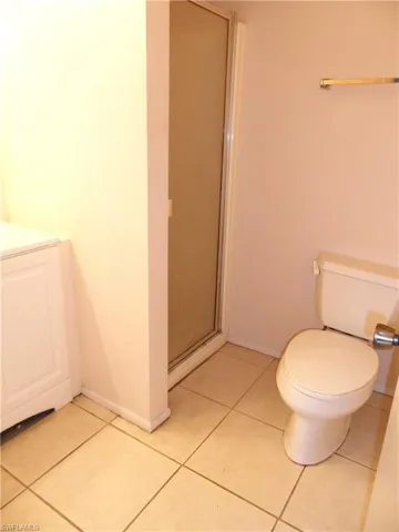 Master bathroom with vanity, toilet, an enclosed shower, and tile patterned flooring
