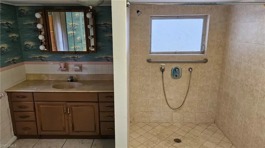 Full bathroom with a tile shower, vanity, and tile patterned floors