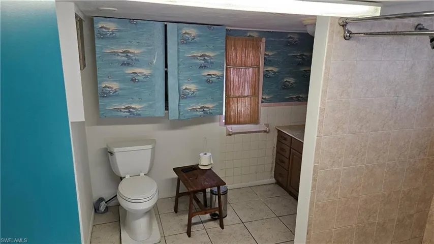 Bathroom with toilet, tile patterned flooring, tile walls, and vanity