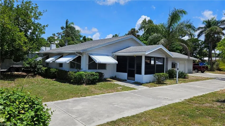 View of front of home with a sunroom, a front yard, a garage, concrete driveway, and a shingled roof
