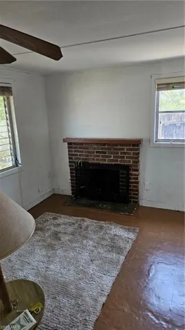Unfurnished living room with a brick fireplace and plenty of natural light