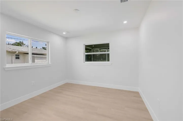 Empty room with light wood finished floors, visible vents, baseboards, and recessed lighting