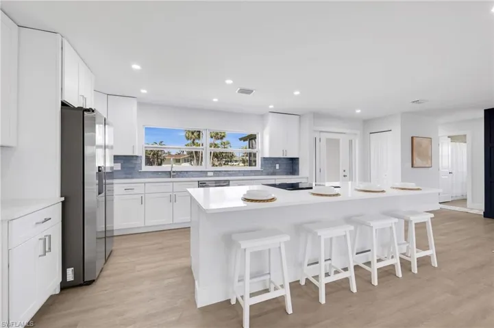 Kitchen with appliances with stainless steel finishes, light countertops, white cabinets, and a kitchen island