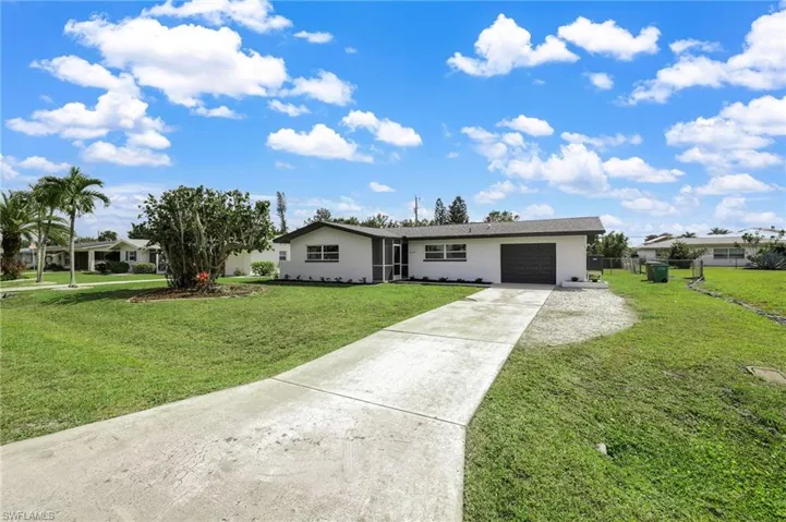Single story home with stucco siding, fence, a garage, driveway, and a front lawn