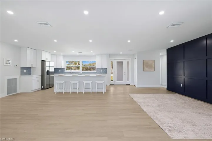 Kitchen featuring visible vents, stainless steel refrigerator with ice dispenser, and a breakfast bar area