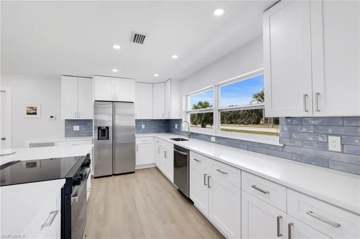 Kitchen featuring visible vents, light wood-style flooring, stainless steel appliances, light countertops, and a sink