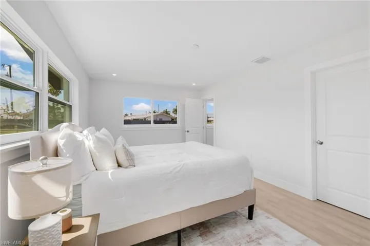 Bedroom featuring light wood finished floors, baseboards, multiple windows, and visible vents