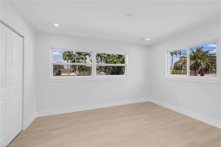Unfurnished bedroom featuring light wood-type flooring, multiple windows, baseboards, and recessed lighting