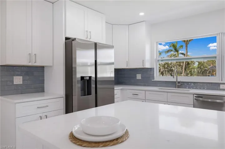 Kitchen featuring a sink, stainless steel appliances, white cabinetry, backsplash, and recessed lighting