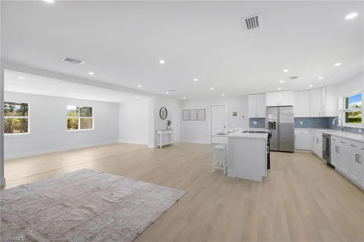 Kitchen with open floor plan, appliances with stainless steel finishes, visible vents, and a center island