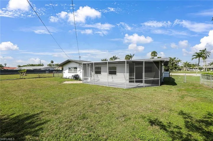 Rear view of property with a sunroom, a patio area, fence, and a lawn