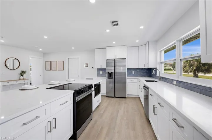 Kitchen featuring visible vents, appliances with stainless steel finishes, light countertops, and a sink