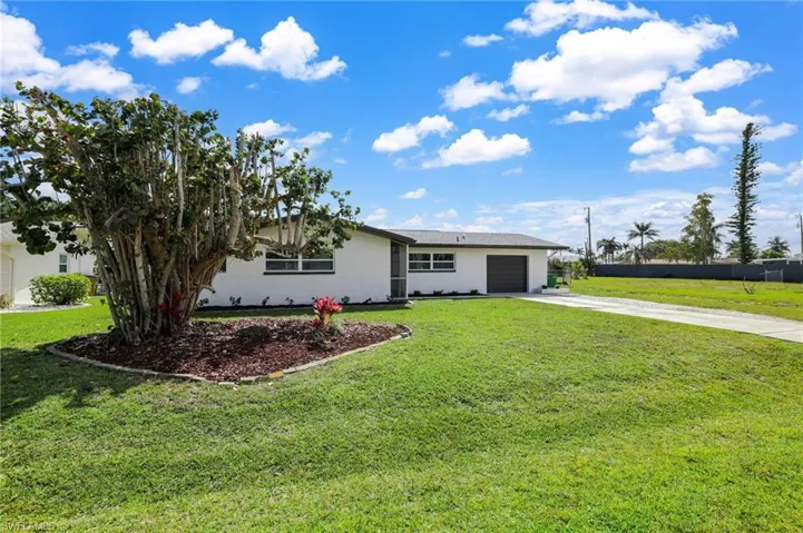 Ranch-style home featuring driveway, a garage, a front lawn, and stucco siding