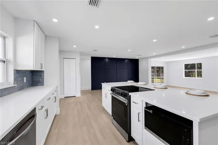 Kitchen featuring visible vents, decorative backsplash, electric range oven, black microwave, and dishwasher