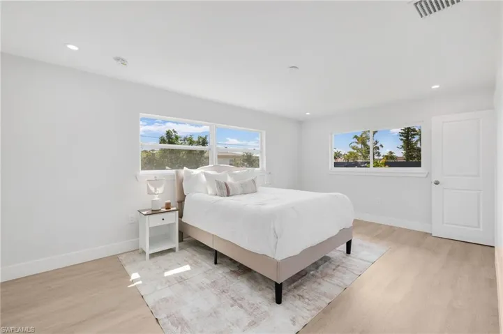 Bedroom featuring baseboards, multiple windows, visible vents, and light wood finished floors