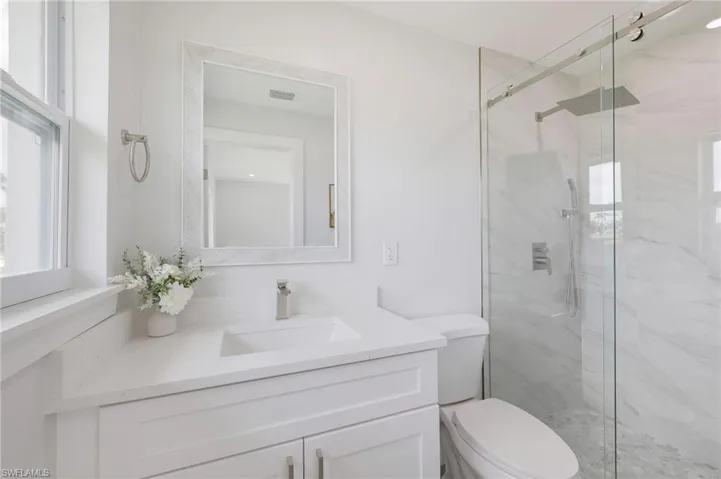 Bathroom featuring visible vents, toilet, vanity, and a marble finish shower