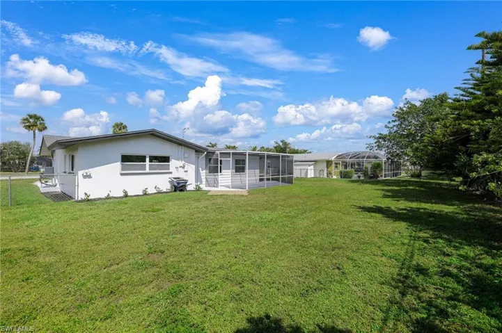 Back of property featuring a lawn, fence, a sunroom, and stucco siding