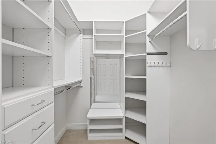 Built-in closet system featuring multiple shelves, hanging rods, drawers with brushed nickel pulls, angled shelving, and integrated hooks