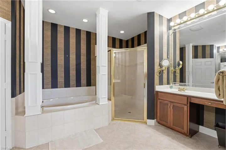 Integrated soaking tub with tiled surround, separate shower with framed glass enclosure, and a vanity with a built-in makeup area
