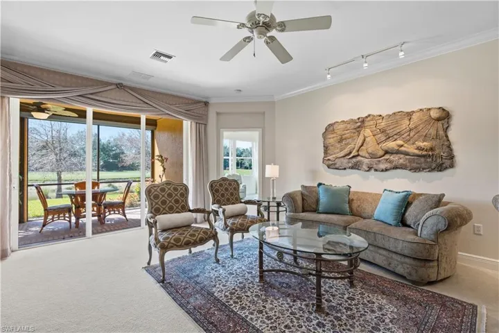 Living area with expansive sliding glass doors, crown molding, a ceiling fan, and carpeted flooring