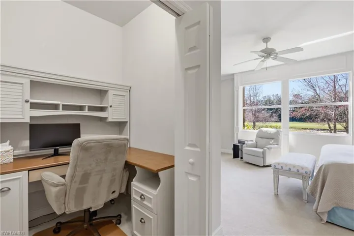 Built-in desk with overhead storage, wood-finish countertop, and white cabinetry