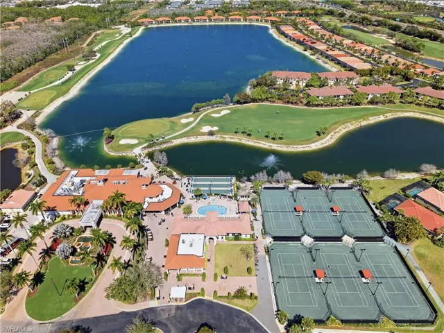 Expansive golf course with multiple greens, large water features, tennis courts, and a central clubhouse with a swimming pool