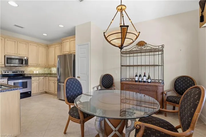 Kitchen featuring stainless steel appliances, wood cabinetry, stone countertops, and tile flooring