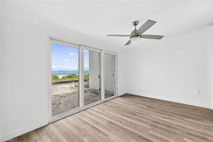 Living room with a water view, crown molding, light wood finished floors, and ceiling fan