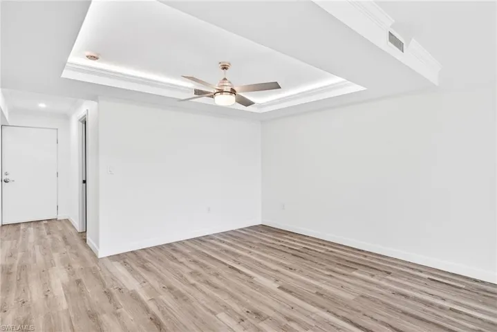 Dining Area with crown molding, a tray ceiling, light wood-style floors, and a ceiling fan