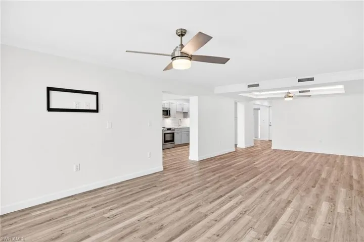 Unfurnished living room featuring a ceiling fan, light wood-type flooring, and crown molding