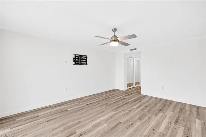 Primary bedroom featuring light wood-style flooring, crown molding, and ceiling fan
