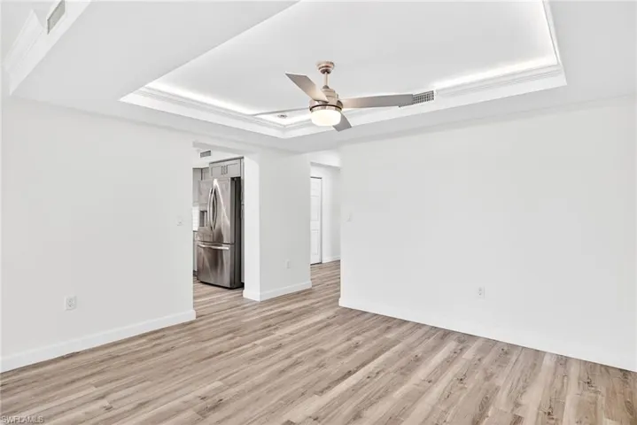 Dining Area featuring a tray ceiling, crown molding, ceiling fan, and light wood-style flooring