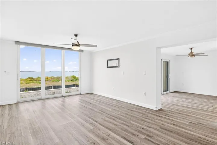 Living room featuring ceiling fan, a water view, floor to ceiling windows, light wood-style floors, and crown molding